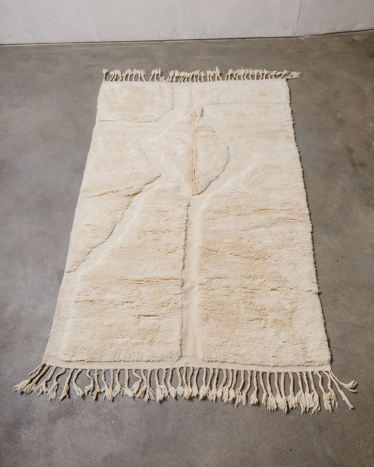 Beige rug with tassels on a concrete floor